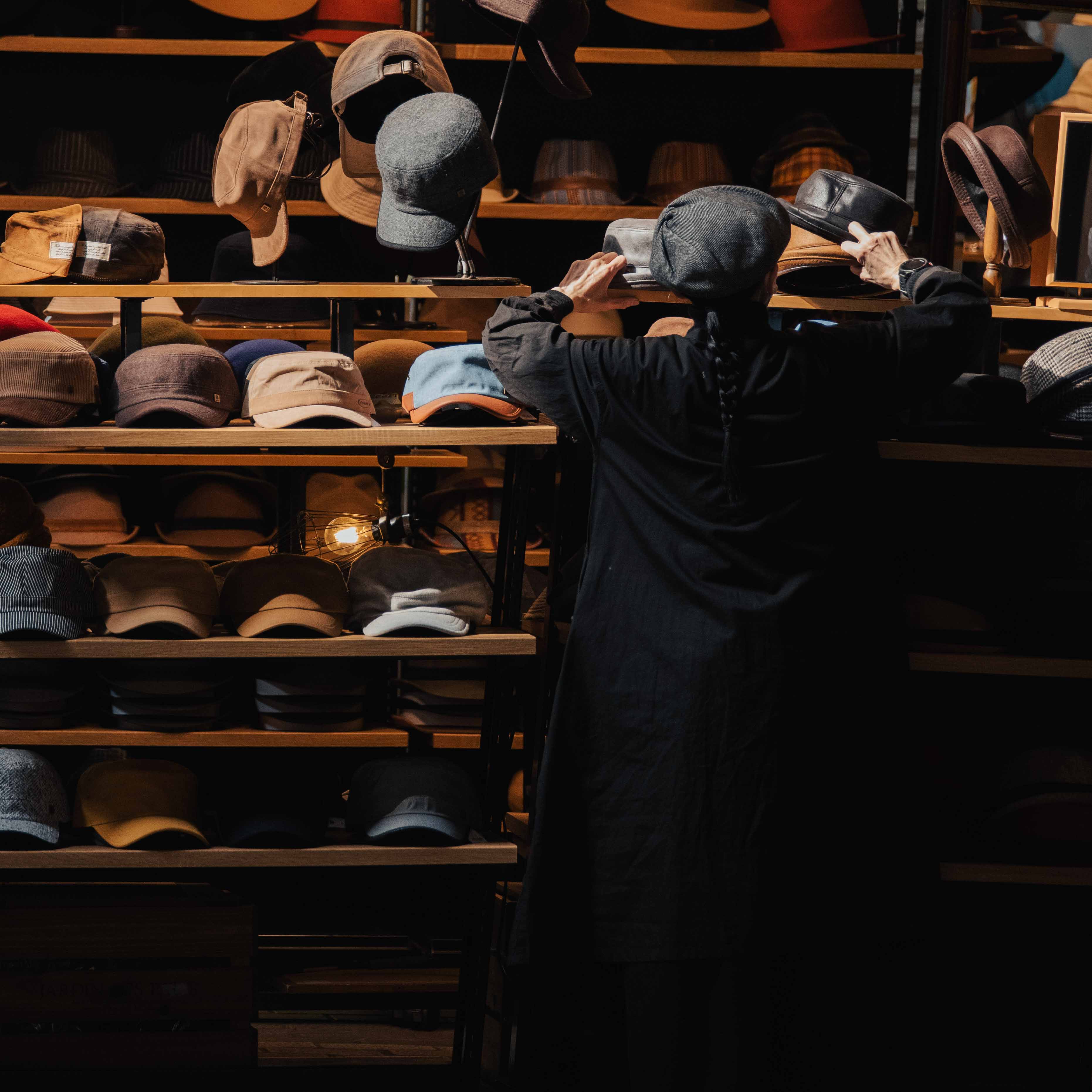 Market store lady adjusts hats